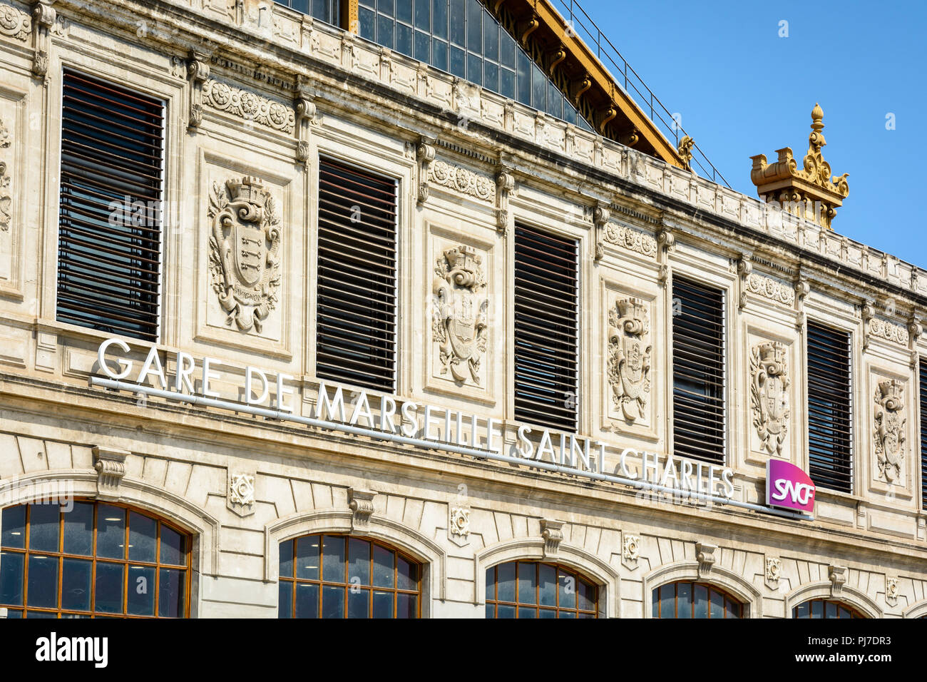 La façade de la gare Saint-Charles à Marseille, France, avec le nom de la station et le logo de la SNCF dans le cadre de l'Armoiries des villes desservies. Banque D'Images