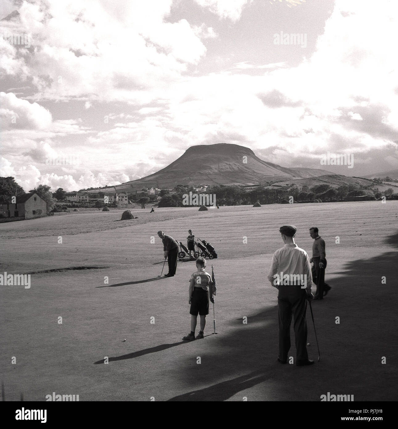 Années 1950, historique, golfeurs jouant au parcours de golf de Cushendall dans le cadre magnifique des Glens d'Antrim, Irlande du Nord, Royaume-Uni. Banque D'Images