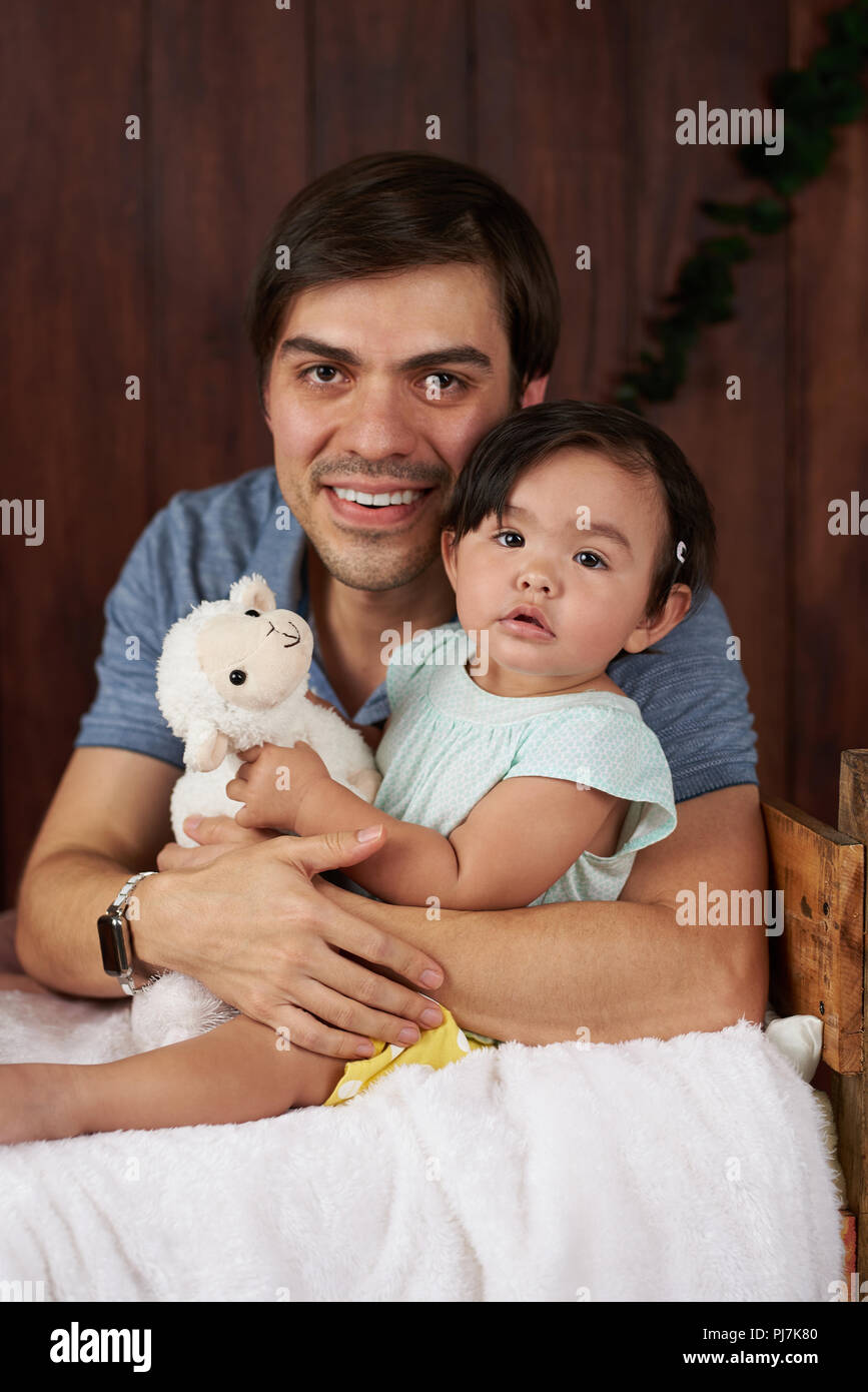 Portrait of father hugging daughter sur fond de studio en bois foncé Banque D'Images