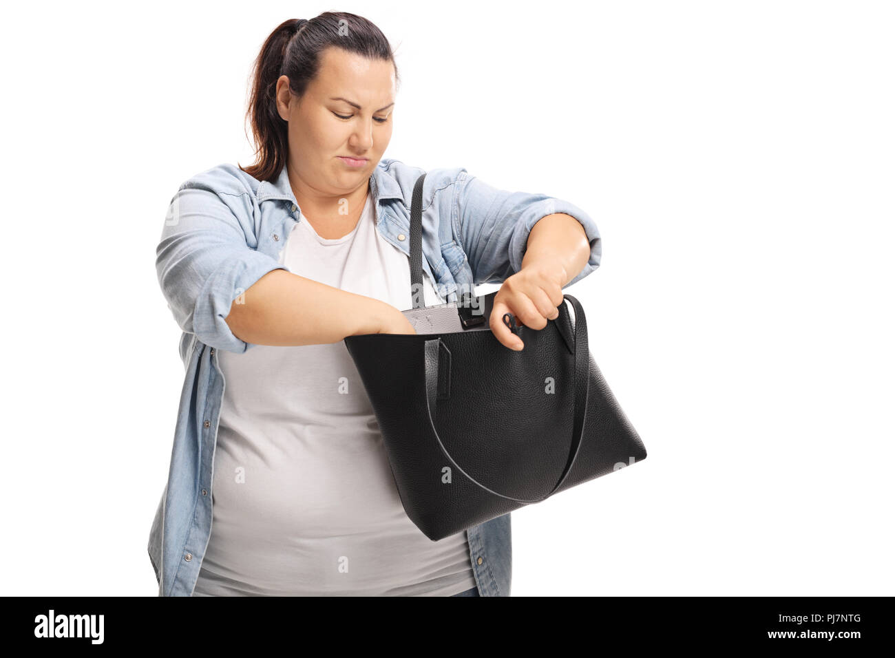 L'excès de femme à la recherche de quelque chose dans son sac à main isolé sur fond blanc Banque D'Images