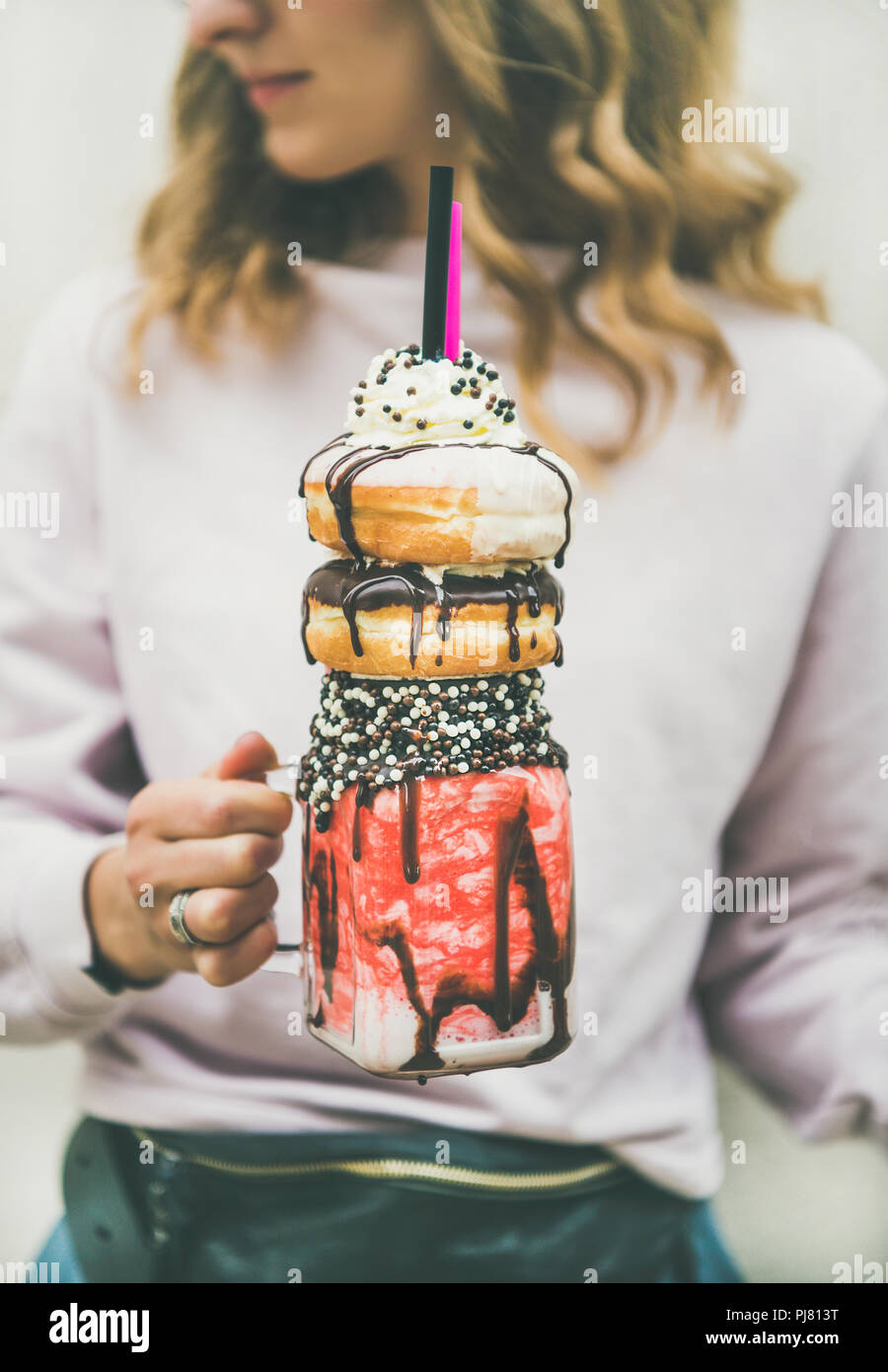 Jeune femme dans des vêtements d'été tenue rose fraise boisson froide donut  freakshake avec crème fouettée en pot Mason en mains, selective focus Photo  Stock - Alamy