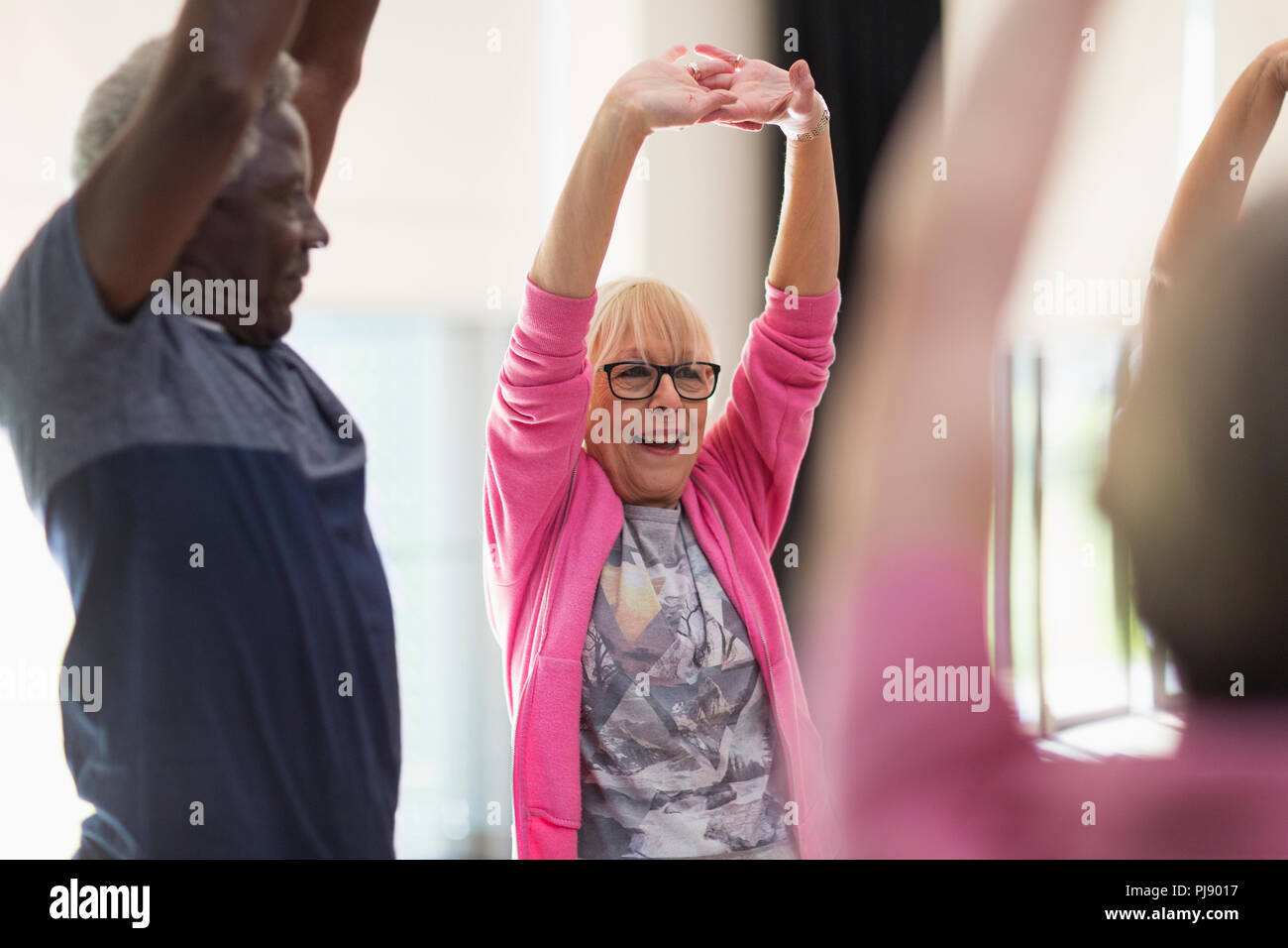 Les personnes âgées actives souriant de l'exercice, stretching arms Banque D'Images