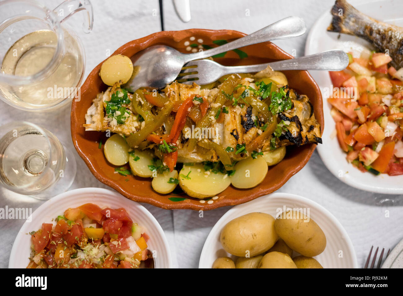 Poisson d'or portugais traditionnel avec du poivre rouge et vert servi avec pommes de terre cuites et tomates en salade Banque D'Images