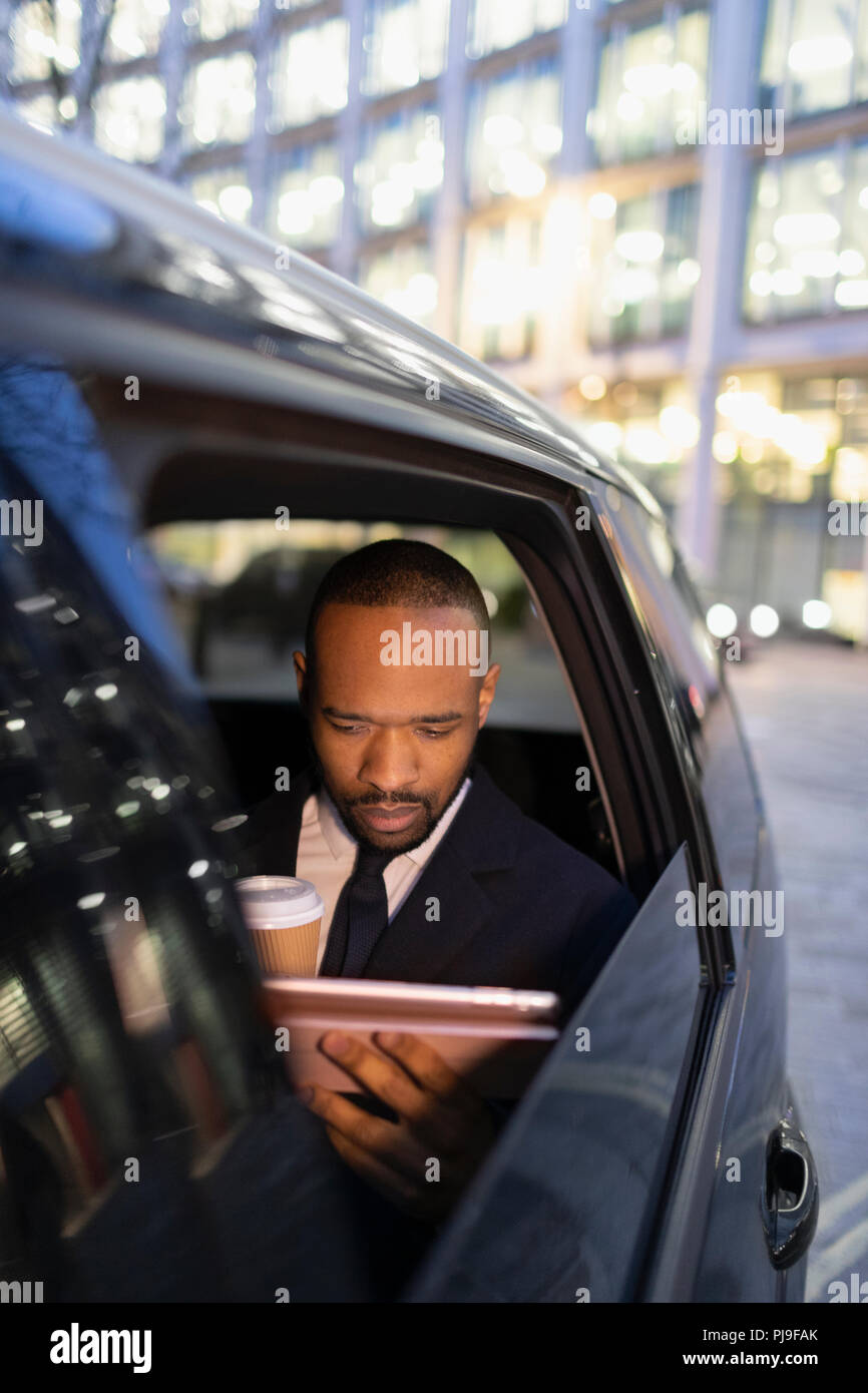 Businessman drinking coffee, using digital tablet in taxi crowdsourcing Banque D'Images