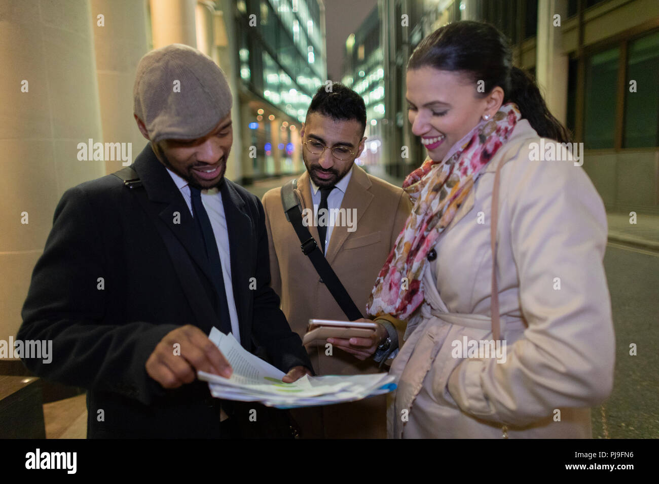 Les gens d'affaires de l'examen de paperasse sur trottoir urbain de nuit Banque D'Images