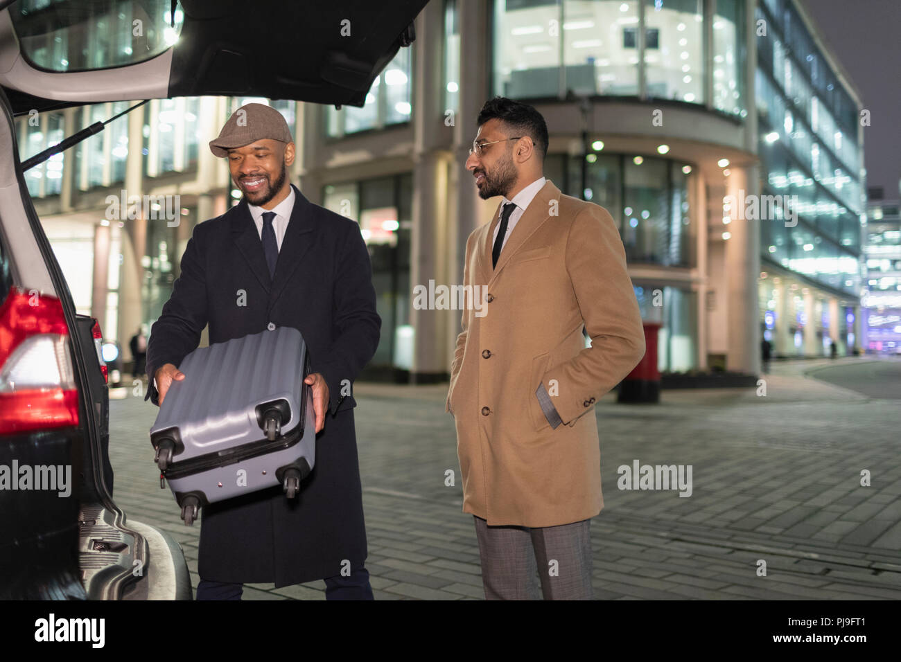 Chargement d'affaires en valise voiture sur coin de rue dans la nuit urbaine Banque D'Images