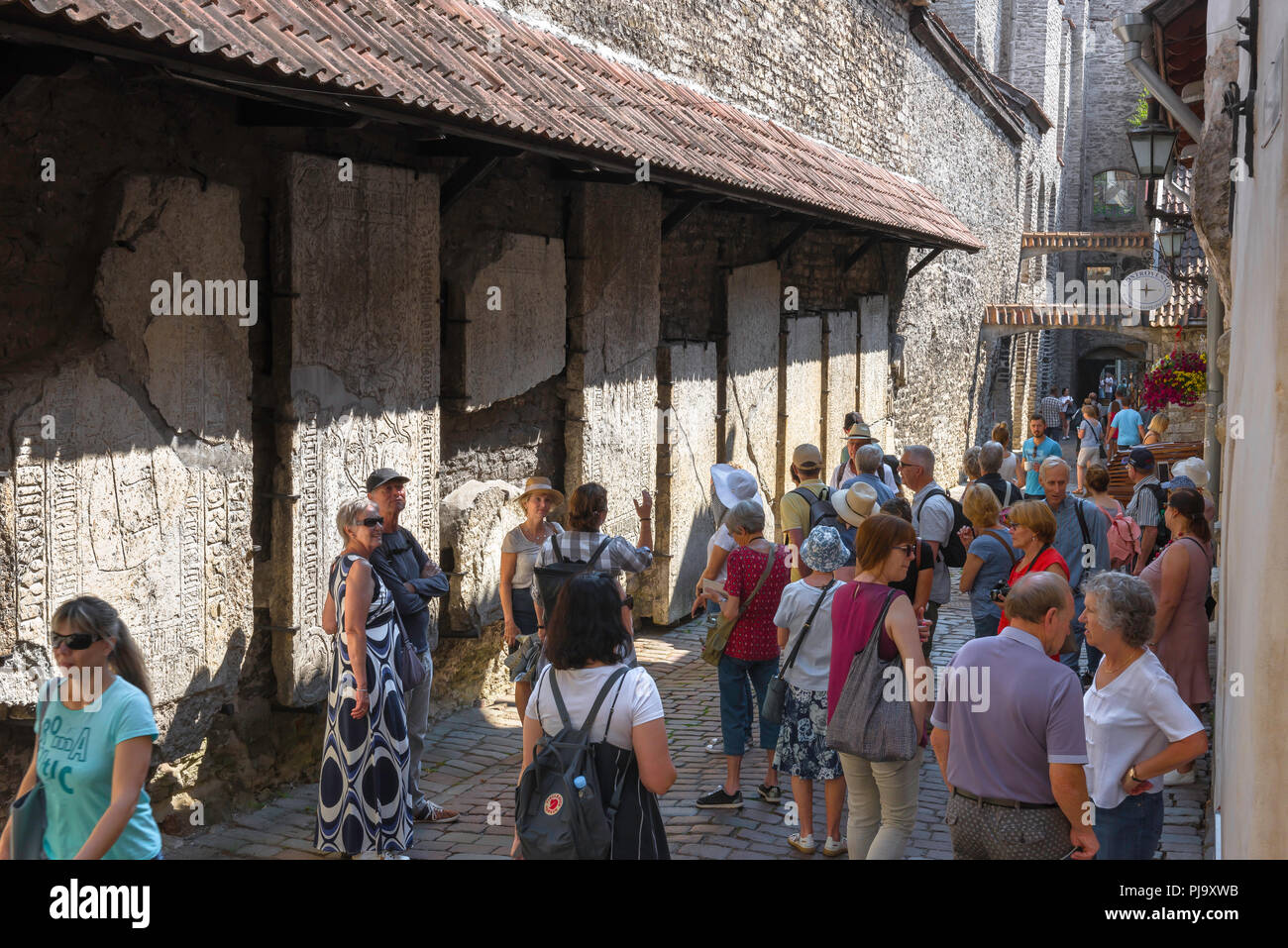 Le tourisme de la mer Baltique, les touristes d'été voir d'énormes pierres tombales médiévales fixés à un mur en Katarina kaik dans la vieille ville de Tallinn, Estonie. Banque D'Images