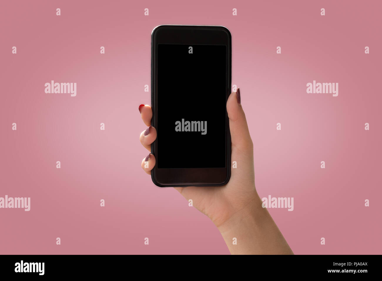 Les femmes Hand holding smartphone noir avec écran noir sur fond rose Banque D'Images