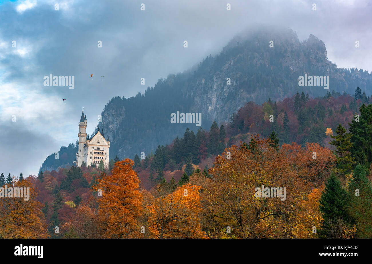 Paysage d'automne colorés avec forêt d'automne, des pics de montagne couverte par les nuages et le château de Neuschwanstein, à Fussen, Bavière, Allemagne. Banque D'Images