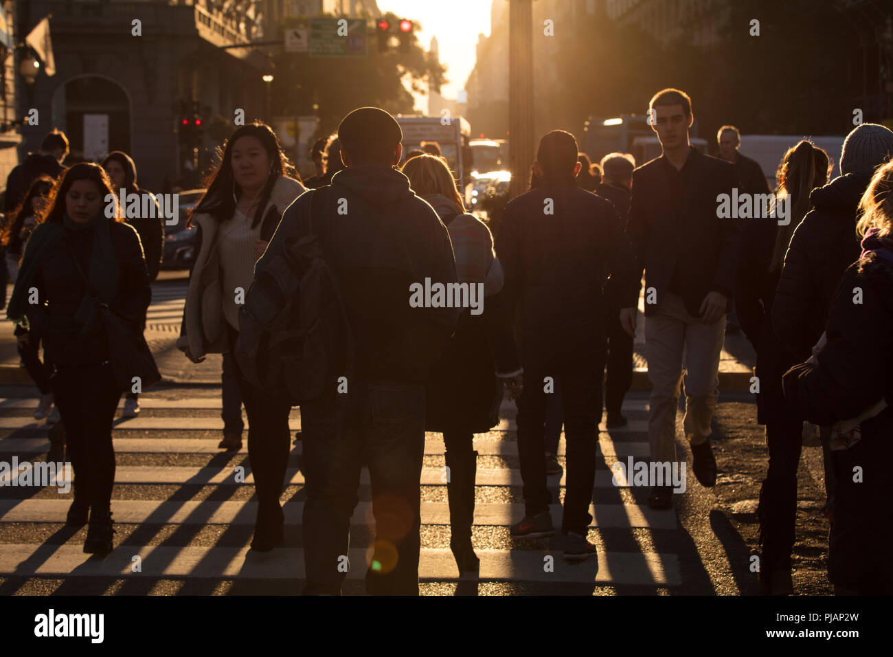 Les personnes qui traversent la route de 'Diagonal Norte' avec l'obélisque en arrière-plan au coucher du soleil. Buenos Aires, Argentine. Banque D'Images
