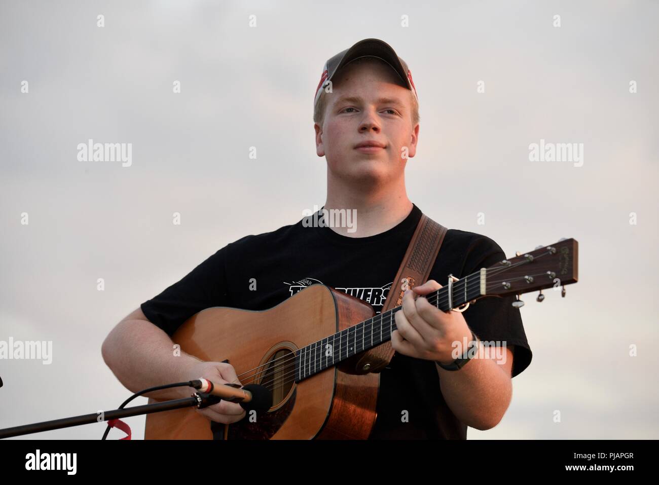La musique bluegrass jeune artiste jouant de la musique live sur sa guitare  à l'extérieur de concert dans la campagne au coucher du soleil, à  l'extérieur de Monroe, Wisconsin, États-Unis Photo Stock -