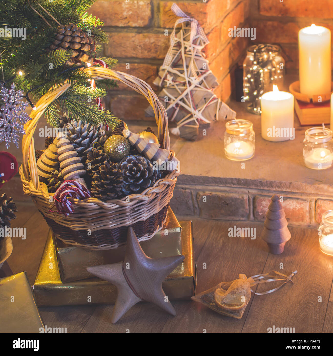 Réglage de Noël arbre de Noël décoré, arrière-plan, des pommes de pin dans le panier, les arbres en bois, poinsettia avec cheminée sur l'arrière-plan, des bougies d'une Banque D'Images