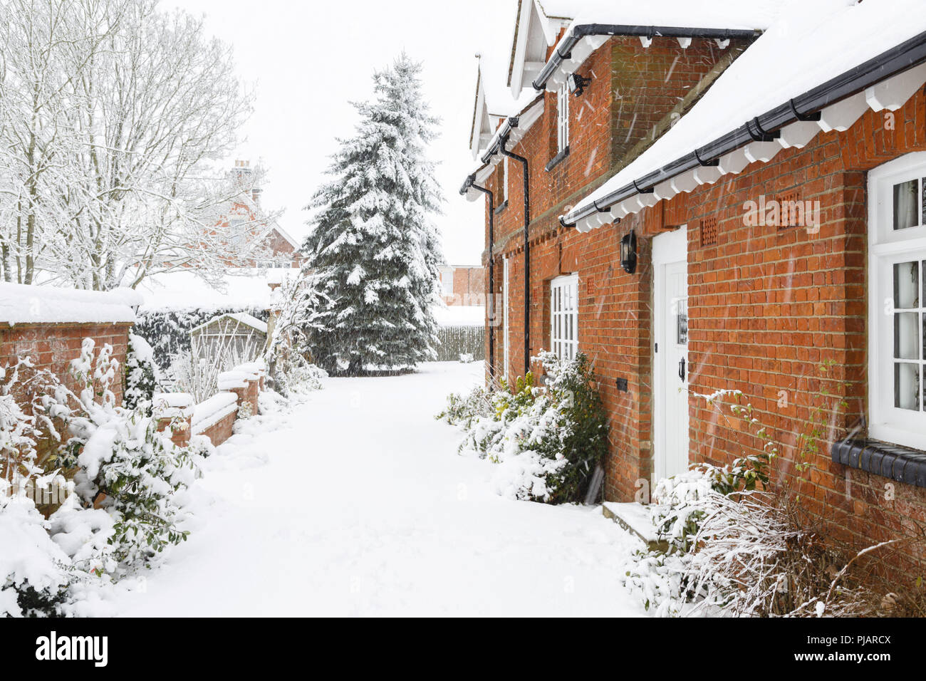 Maison de campagne en hiver avec une allée couverte de neige Banque D'Images