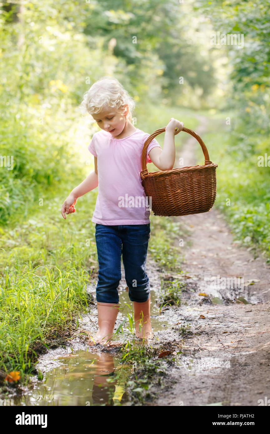 Cute adorable blonde caucasienne preschool little girl picking fresh champignons comestibles dans panier en osier. L'activité de l'automne automne hobby concept. Banque D'Images