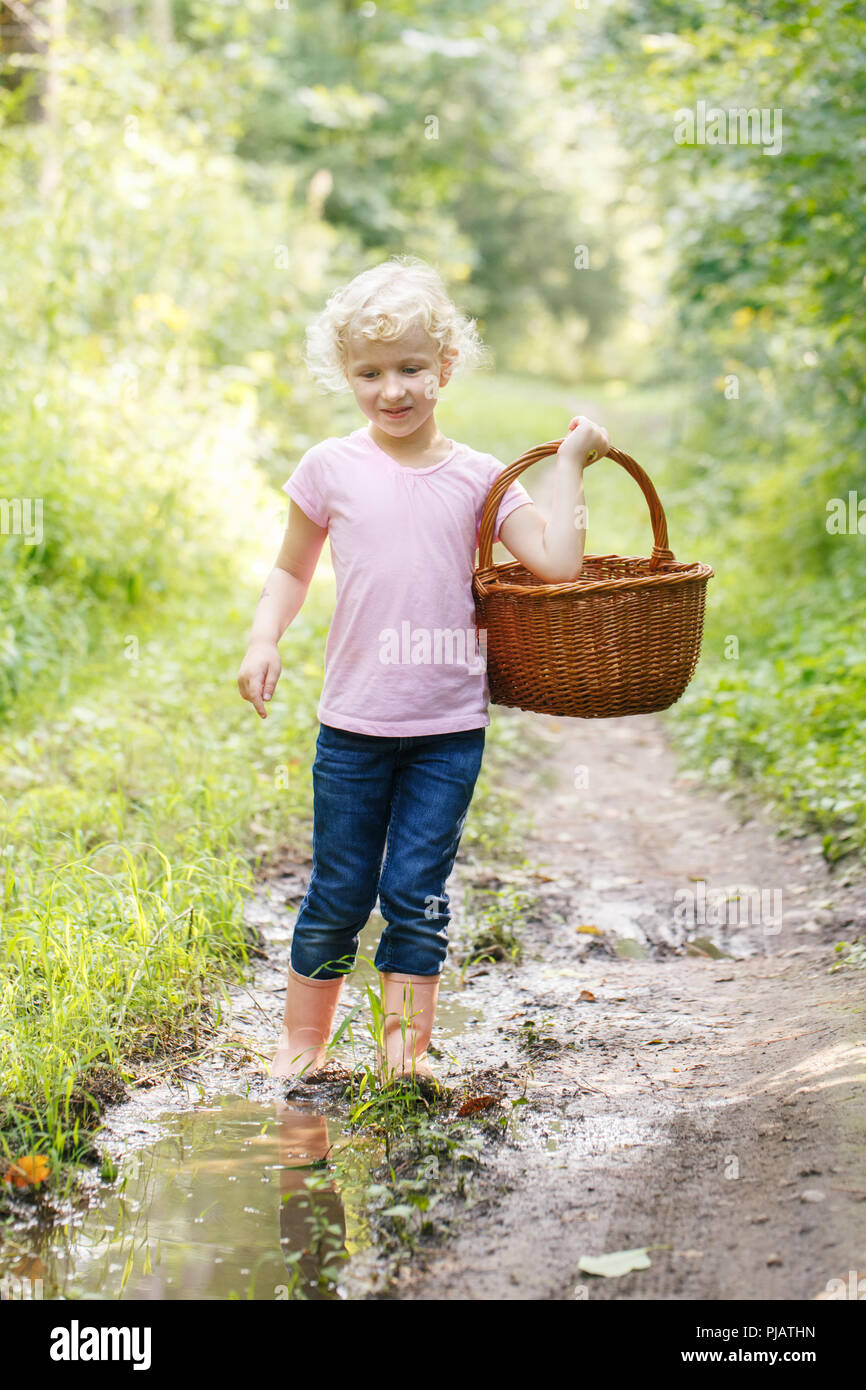 Cute adorable blonde caucasienne preschool little girl picking fresh champignons comestibles dans panier en osier. L'activité de l'automne automne hobby concept. Banque D'Images