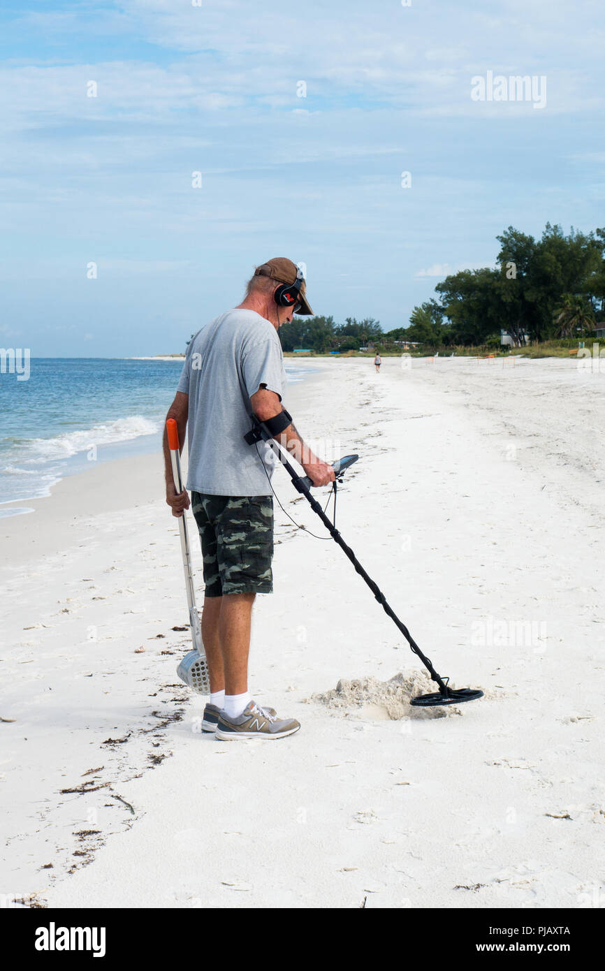 Un homme utilise un détecteur de métal pour rechercher des trésors sur l'Anna Maria Island Beach, Florida, USA Banque D'Images