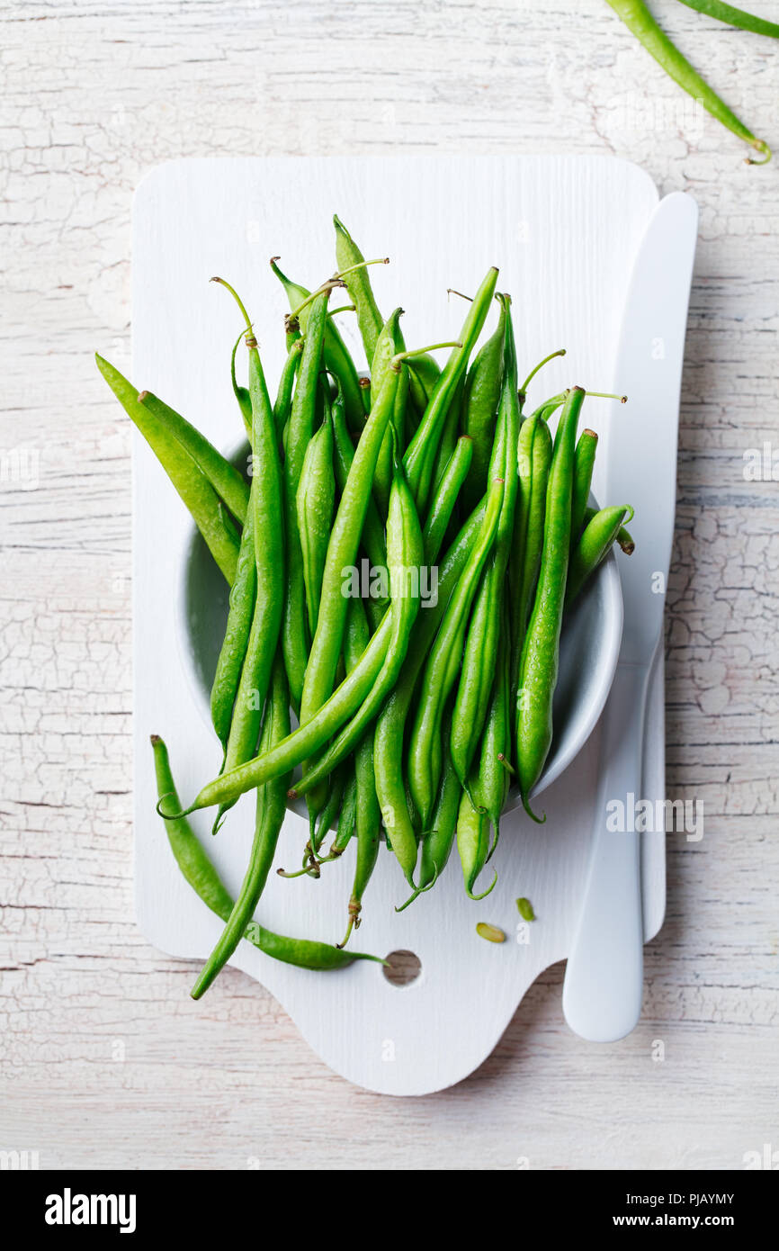 Haricots verts en bol blanc sur une planche à découper. Vue d'en haut. Copier l'espace. Banque D'Images