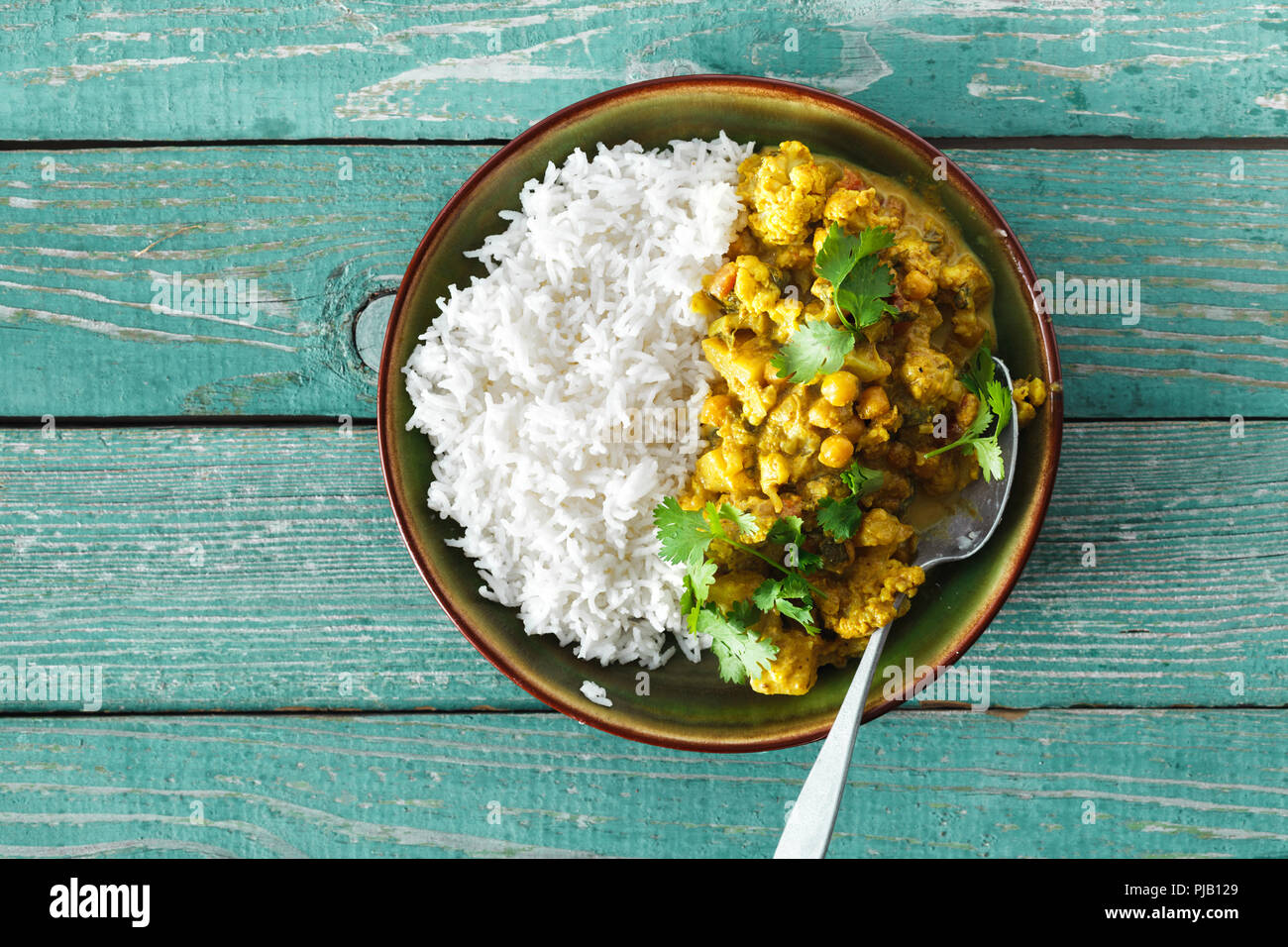 Le chou-fleur curry épicé avec du riz sur fond de bois vert copie espace Vue de dessus Banque D'Images