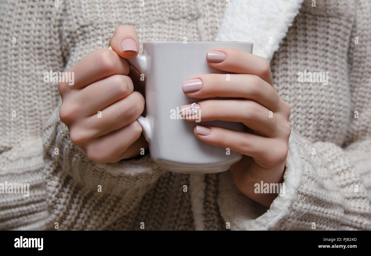 Belles femmes beige chaud avec nail design holding white cup. Banque D'Images