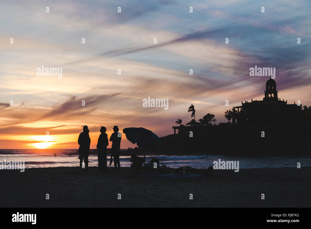 Les amis debout sur une plage mexicaine regardant un coucher de soleil. Banque D'Images