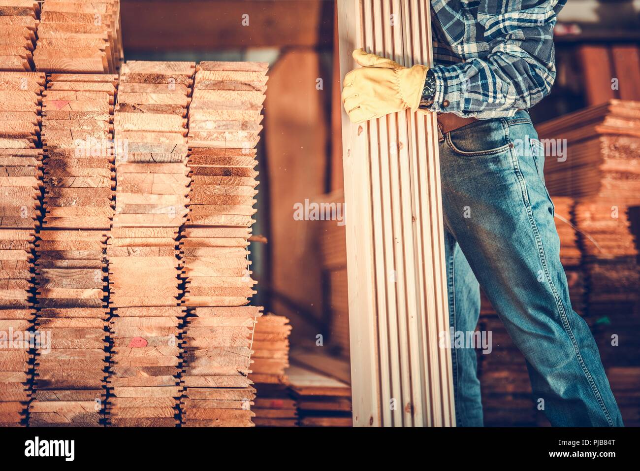 Entrepreneur avec des planches. Charpentier caucasien avec des tas de bois. Thème Matériaux de construction. Banque D'Images