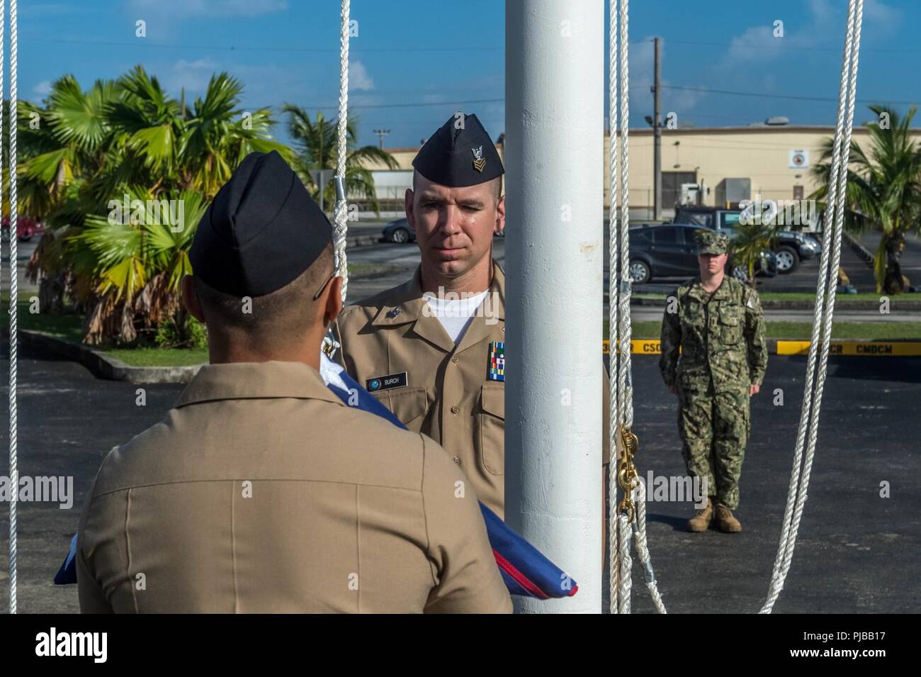 SANTA RITA, Guam (1 juillet 2018) Yeoman 1re classe Travis Aquino, à gauche, et l'opérateur de l'équipement 1re classe Clinton Burch se préparent à relever le drapeau américain sur le 30e Régiment de la construction navale (RCN) siège, marquage officiellement sa réinstallation à Guam de Port Hueneme, en Californie. Cette mesure simplifie l'efficacité opérationnelle et établit le régiment en tant que l'avant-déployé du personnel opérationnel capable de commander et de contrôler les unités de la Force de la construction navale déployée pour la 7e flotte zone d'opérations. Banque D'Images