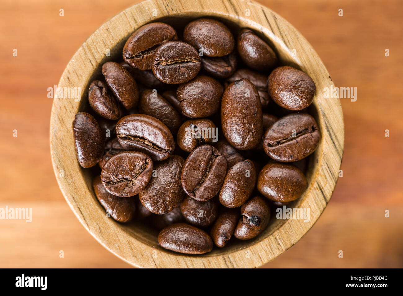 Les grains de café torréfié dans bol en bois. Banque D'Images