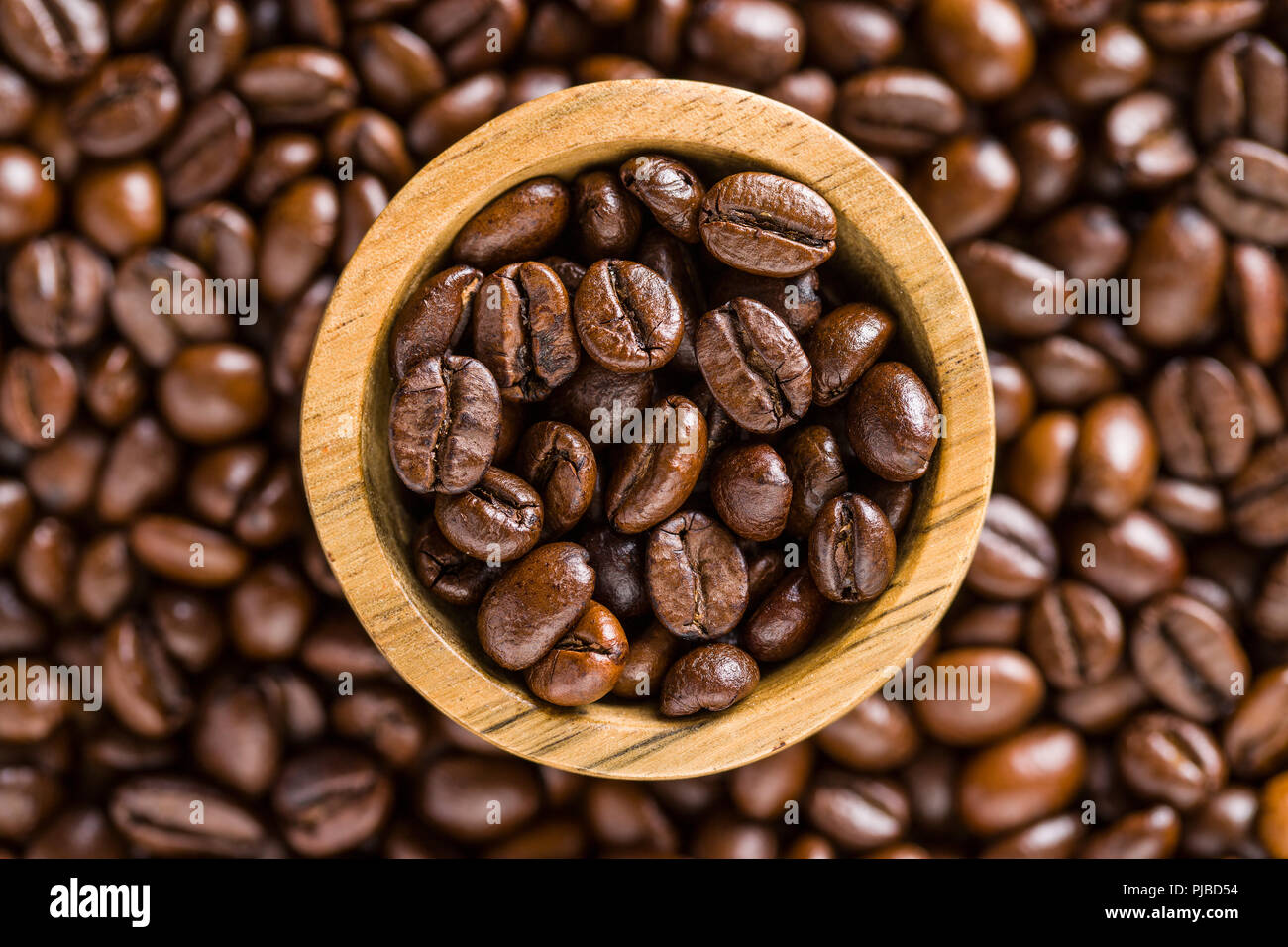 Les grains de café torréfié dans bol en bois. Banque D'Images