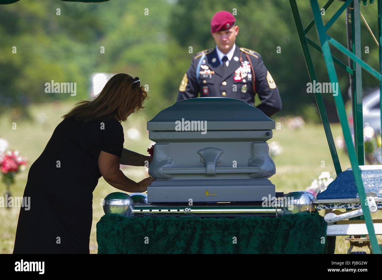 Un membre de la famille des retraités 1er Sgt. Harold Eatman, gauche, met une fleur sur son cercueil lors Sharon Memorial Park de Charlotte, Caroline du Nord le 11 juillet comme 1er Sgt. James Miller, droite, d'entreprise, B, 2e Bataillon du 505th Parachute Infantry Regiment. Eatman a été membre de la 505ème PIR durant la Seconde Guerre mondiale, faisant combattre saute dans la Sicile, Salerne, la Normandie et la Hollande. Eatman est décédée au début de juillet à l'âge de 102 ans. Banque D'Images