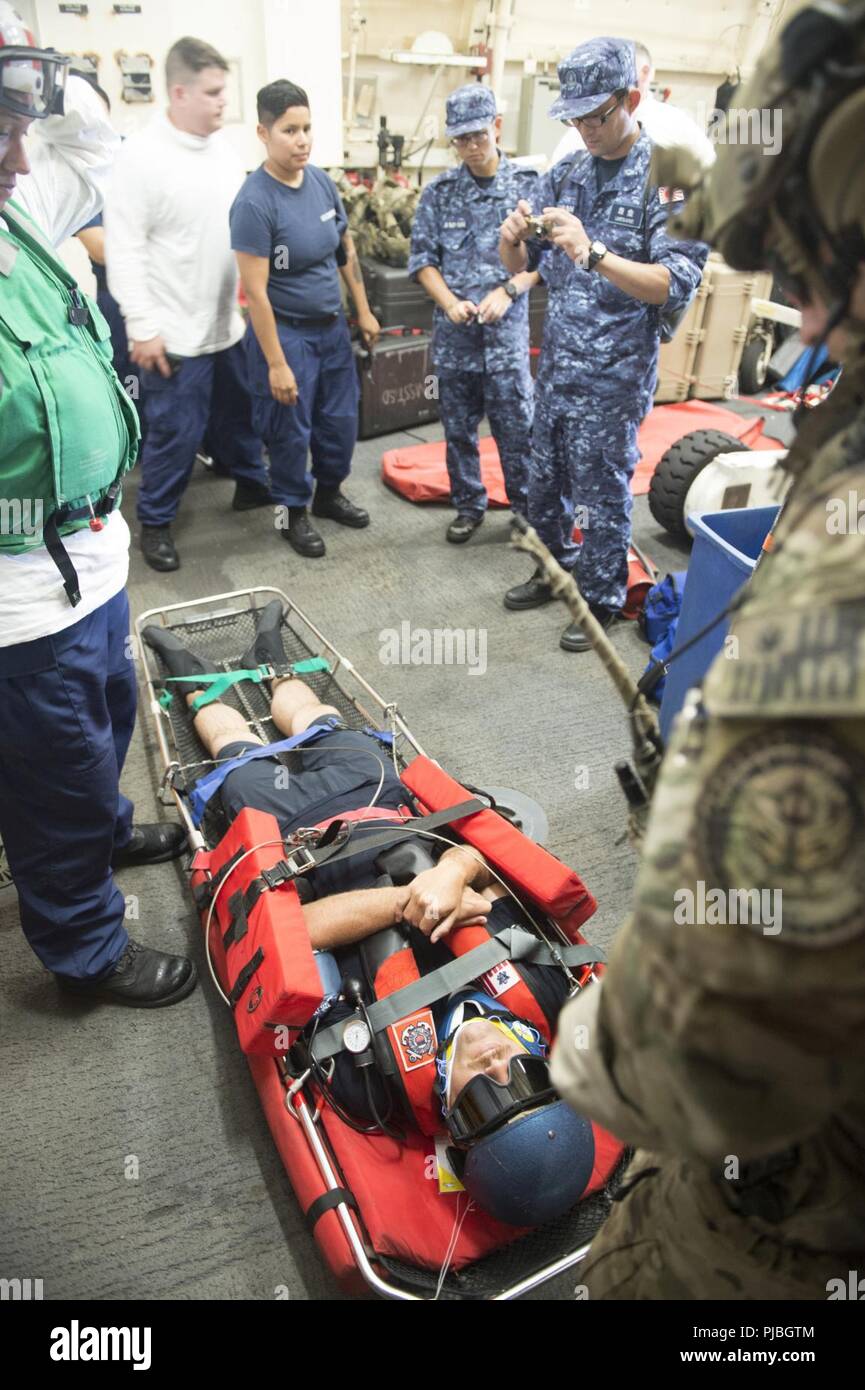 Océan Pacifique (11 juillet 2018) Maître de 1re classe Nicklas Gerzi est prêts pour une évacuation sanitaire par l'équipage du USCGC Bertholf (WMSL 750) et de la Garde côtière Maritime Security Response Team-West 11 juillet 2018, alors que l'équipage du Japon d'autodéfense maritime navire hélicoptère destroyer DDH 182 JS (ISE) observer, 15 milles au sud-ouest d'Oahu, Hawaii, à l'appui de l'exercice RIMPAC 2018. Vingt-cinq nations, plus de 46 navires et 5 sous-marins, environ 200 avions et 25 000 personnes participent à l'EXERCICE RIMPAC du 27 juin au 2 août dans et autour de l'île hawaïenne et du sud de la Californie. Le wor Banque D'Images