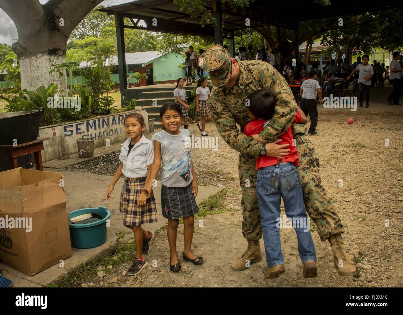 U.S. Marine 1er Sgt. Jeremy Surratt, l'élément logistique company premier sergent avec des Groupe de travail air-sol marin - région Sud, étreignant un enfant guatémaltèque locales tout en menant une étude de site d'une école de la Marine sur la remise du plan de Flores, Guatemala, le 9 juillet 2018. Les Marines et les marins d'SPMAGTF-SC mènent la coopération de sécurité et de formation projets d'ingénierie avec des forces militaires de la nation d'Amérique centrale et du Sud. L'unité est également prêt à fournir une aide humanitaire et des secours en cas d'ouragan ou autre situation d'urgence Banque D'Images