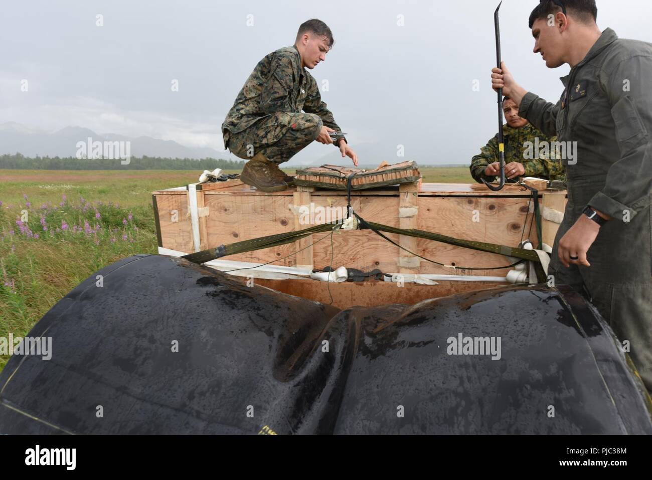 Corps des Marines des États-Unis Le Cpl. Gavin Huegel et le Sgt. Brett Nelson avec le soutien de Transport 3d Bataillon, Régiment de logistique de combat 3, 3d Marine Logistics Group de Okinawa Japon ouvrir un ensemble d'équipement lourd après qu'il ait atterri sur la zone de largage Malemute, Juillet 16, 2018 at Joint Base Elmendorf-Richardson, en Alaska. La formation faisait partie d'un exercice de 12 jours, appelé Kodiak Mace qui incorporated C-130J Super Hercules cargo appartenant à l'Escadron de transport de ravitaillement aérien maritime (VMGR) 152 et des marines de la BST, 3d, 3d-3 CLR MLG. L'eau a été utilisé pour simuler la pompe à carburant. Banque D'Images