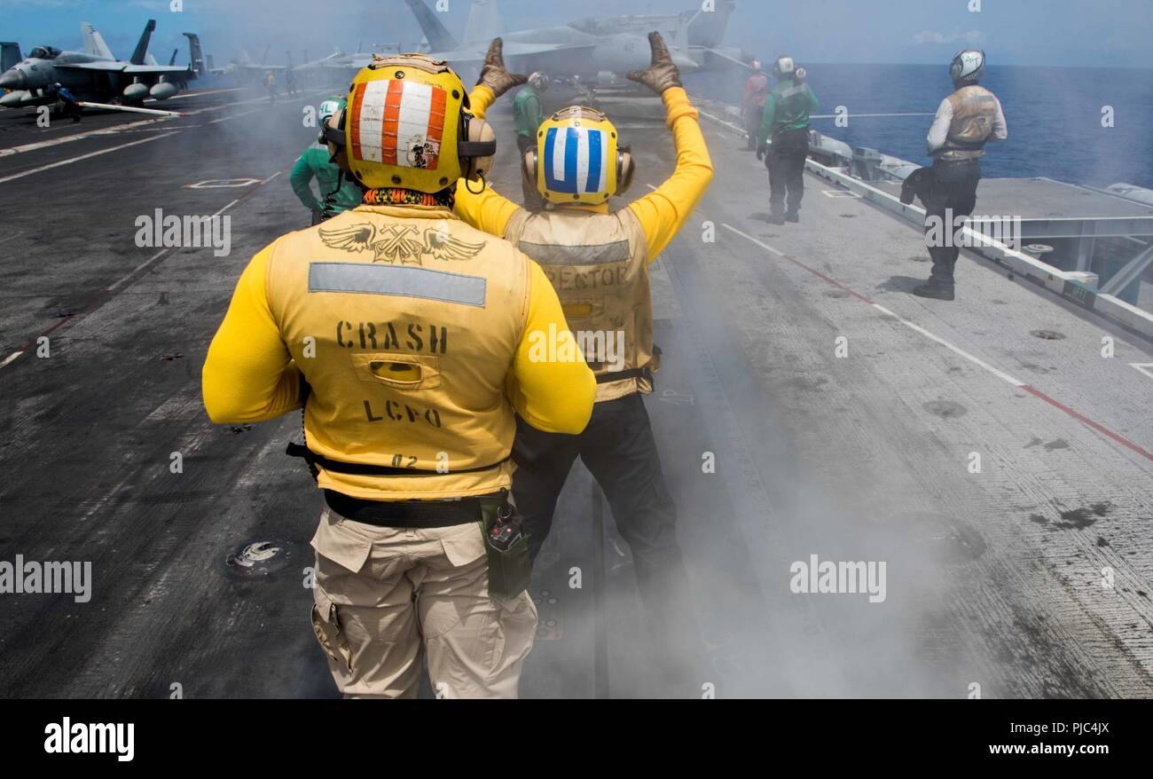 Mer des Philippines (13 juillet 2018) l'aviation en chef Maître de Manœuvre (manutention) Diego Salvador, de Miami, observe maître de Manœuvre de l'Aviation (manipulation) d'un membre de la Jordanie Cox, de Joplin, Missouri, d'un aéronef dans le poste de pilotage de la marine de l'avant-déployé, porte-avions USS Ronald Reagan (CVN 76). Ronald Reagan, le groupe aéronaval du porte-étendard de 5, fournit une force prête au combat qui protège et défend les intérêts de maritime collective de ses alliés et partenaires dans la région Indo-Pacifique. Banque D'Images