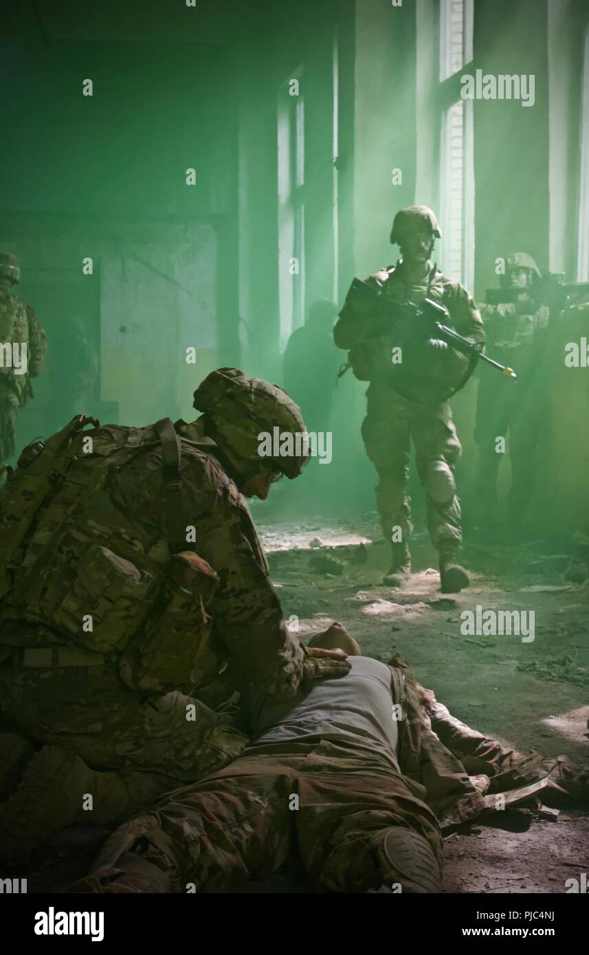 L'viv, Ukraine - Classe 703-2018 Cours de leadership de base indiqué par la commande d'entraînement de l'Armée 7e sous-officiers sur le terrain lors d'un entraînement physique à l'viv Centre d'instruction au combat (CIC) Le 11 juillet. 40 soldats de la 27ème Infantry Brigade Combat Team (avant) ont pris part à la course et comme on le voit ici le Sgt. Robert Majewski de West Seneca, NY, répond à un nombre de blessés et le sergent chef d'escouade. Chris Cormack de Penfield, NY, inspecte la ligne de défense lors de la réception de l'OPFOR contact en milieu urbain Milieu de formation. Banque D'Images