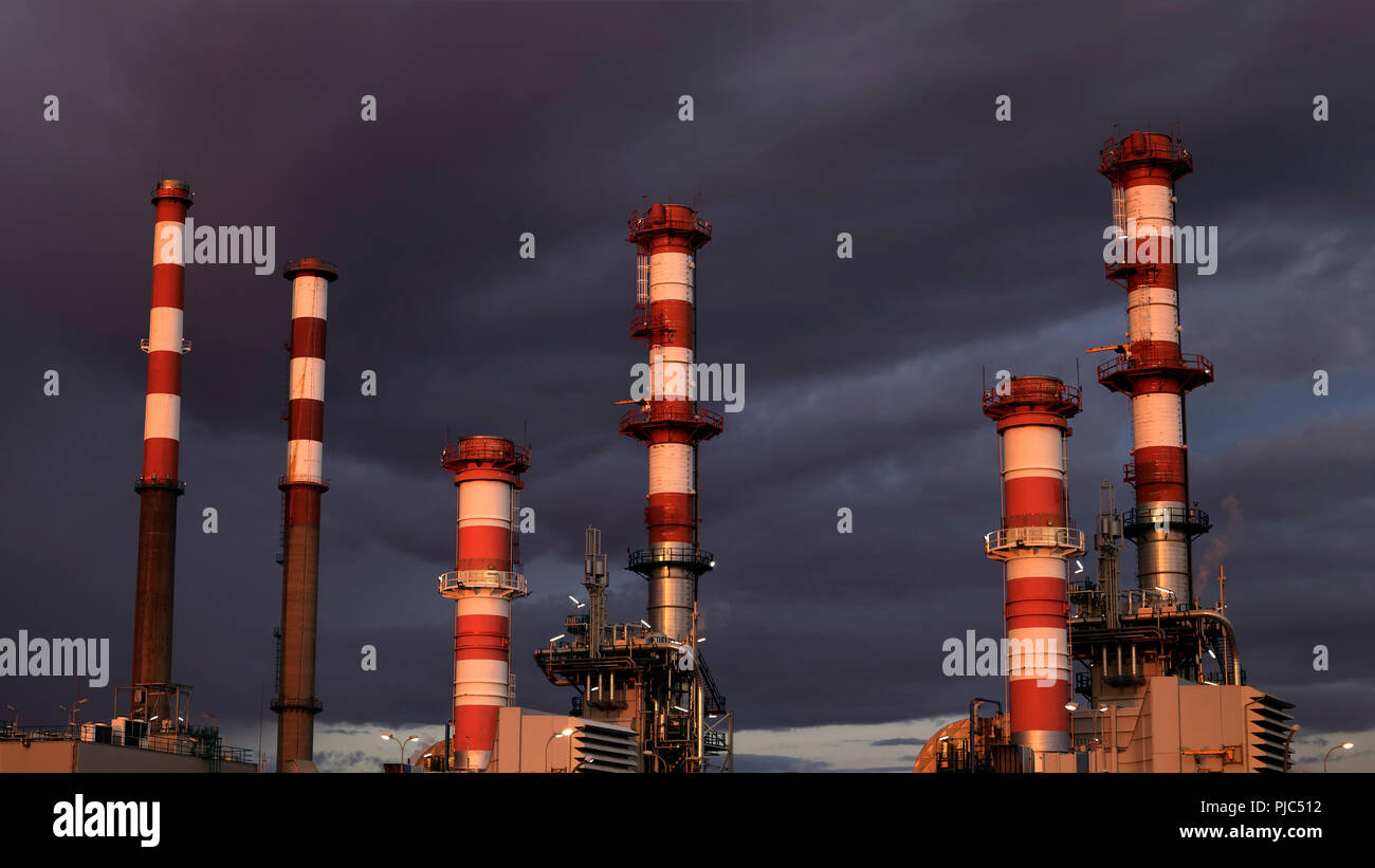 Partie d'une grande raffinerie de pétrole et les cheminées de la centrale au crépuscule Banque D'Images