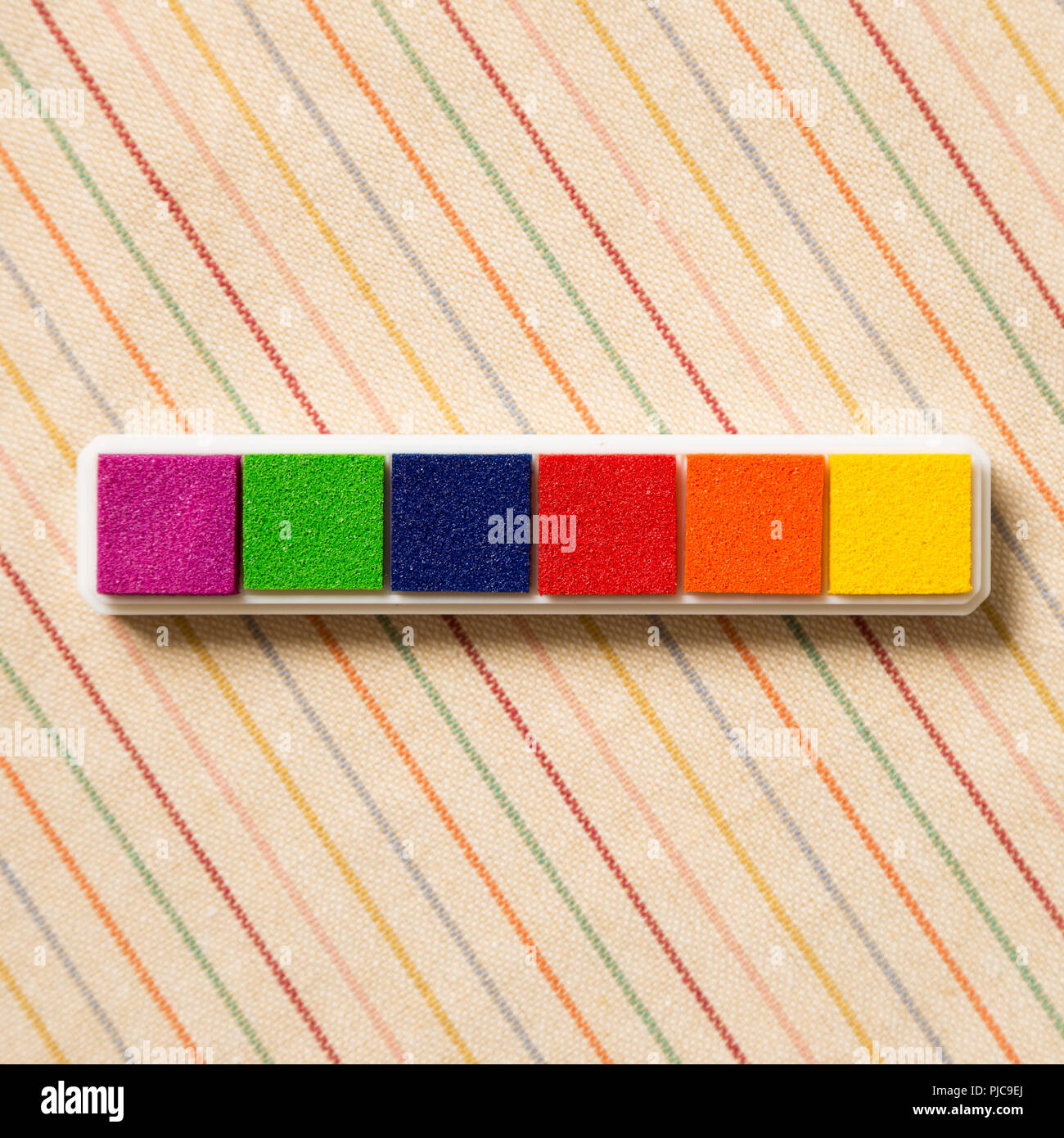 Tampon encreur timbre coloré motif hachuré sur fond de tissu Banque D'Images