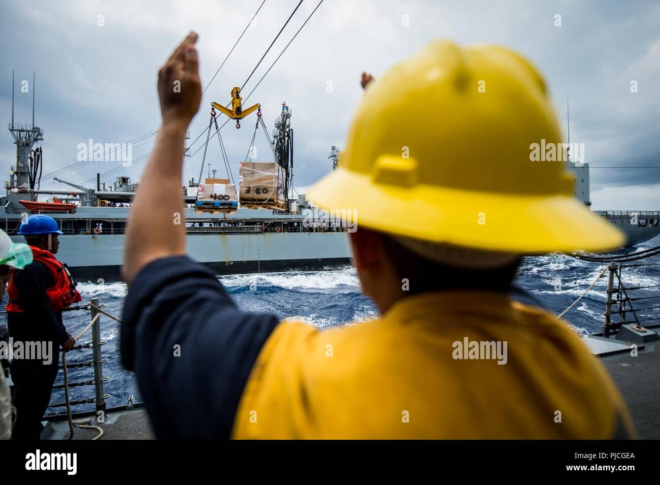 Océan (20 juillet 2018) - Maître de Manœuvre 2e classe Jorge, Kenyelis de Eau Claire, Wisconsin, des signaux à la reconstitution de la flotte oiler USNS Henry J. Kaiser (T-AO 187) que les palettes de vivres et de fournitures l'approche missiles USS Dewey (DDG 105) connecté au cours d'une reconstitution. Dewey est en cours aux États-Unis de la flotte de 3ème zone d'opérations. Banque D'Images