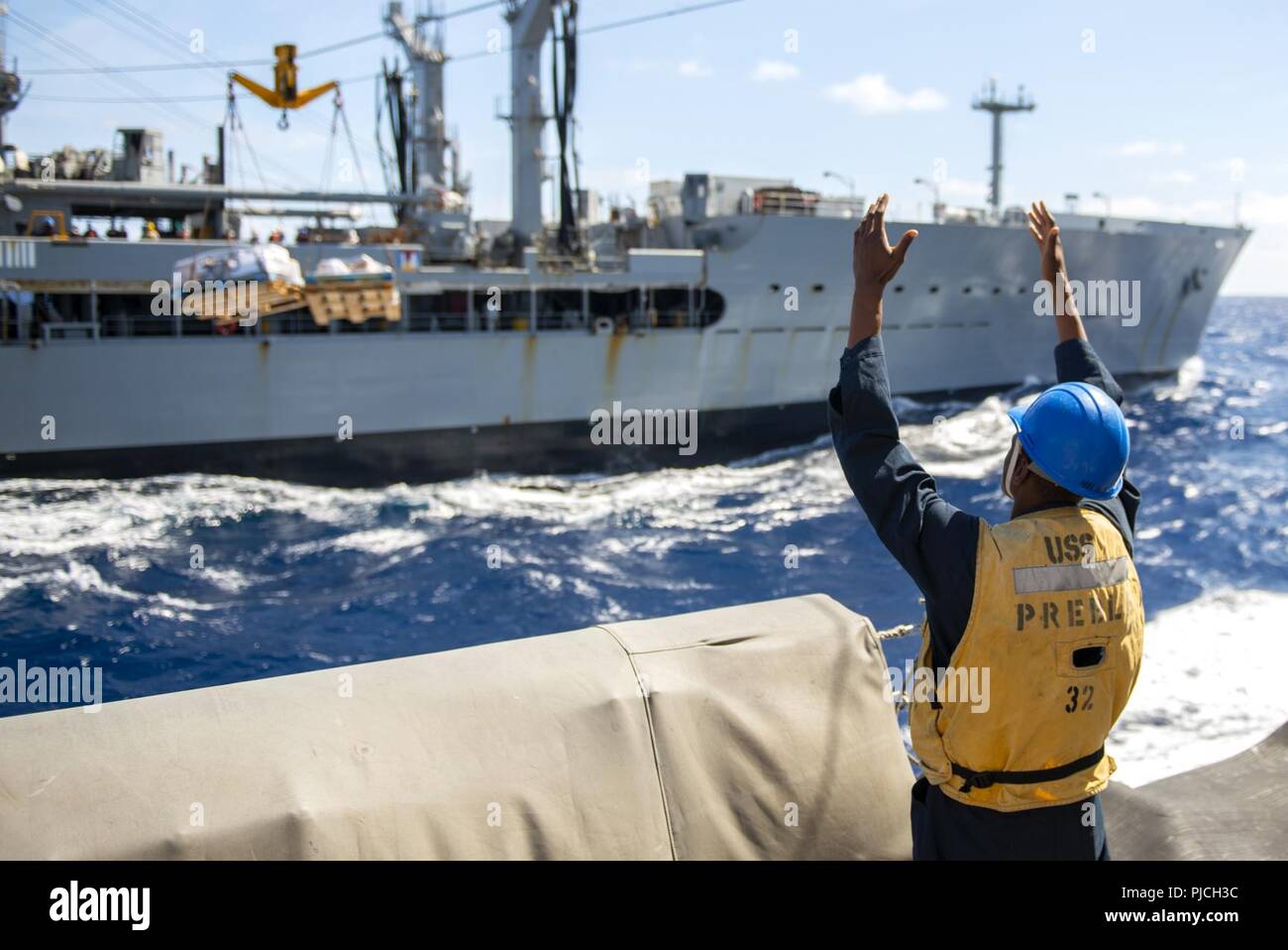 En Mer (21 juillet 2018) Maître de Manœuvre 2e classe Johnny Gray pour les signaux de commande de transport maritime militaire (MSC) reconstitution de la flotte oiler USNS Henry J. Kaiser (T-AO 187) pour envoyer des missiles de palettes à destroyer USS Preble (DDG 88) au cours d'un ravitaillement en mer pendant l'exercice Rim of the Pacific (RIMPAC). Vingt-cinq nations, 46 navires, 5 sous-marins, et d'environ 200 avions et 25 000 personnes participent à l'EXERCICE RIMPAC du 27 juin au 2 août dans et autour des îles Hawaï et la Californie du Sud. Le plus grand exercice maritime international RIMPAC, fournit une occasion de formation unique Banque D'Images