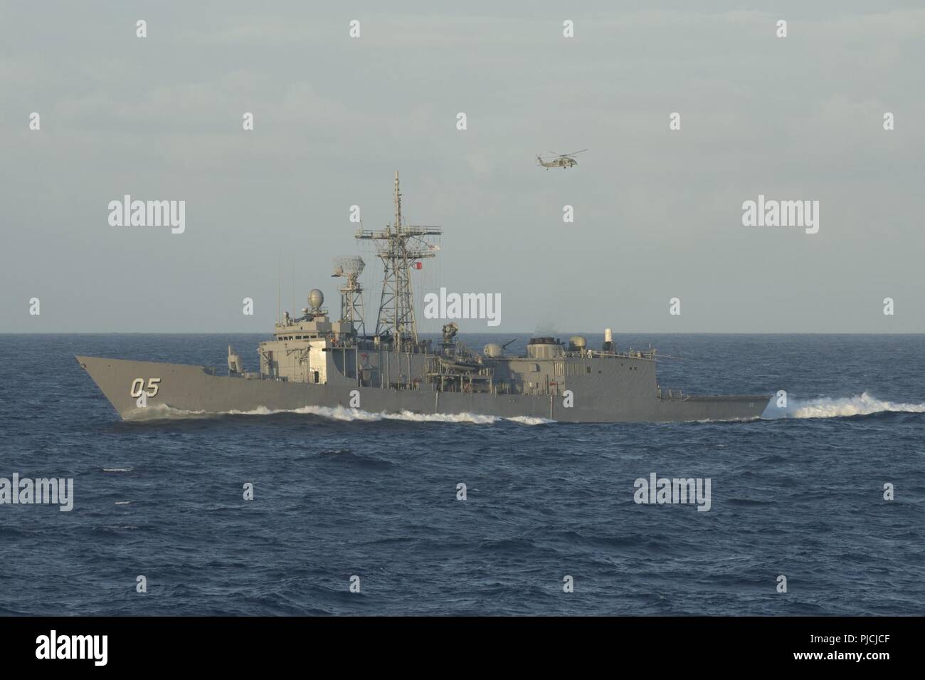 Océan Pacifique (Juillet 21, 2018) de la Royal Australian Navy la frégate lance-missiles HMAS Melbourne (FFG 05) transits l'océan Pacifique, tandis qu'un MH-60 de la Marine américaine Sea Hawk vole au-dessus au cours de l'exercice Rim of the Pacific (RIMPAC). Vingt-cinq nations, 46 navires, 5 sous-marins, et d'environ 200 avions et 25 000 personnes participent à l'EXERCICE RIMPAC du 27 juin au 2 août dans et autour de l'île hawaïenne et du sud de la Californie. Le plus grand exercice maritime international RIMPAC, fournit une formation unique alors que la promotion et le soutien des relations de coopération, Amon Banque D'Images