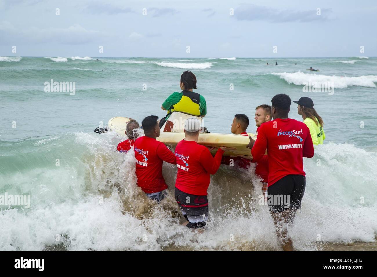 Les Marines américains avec 3e Régiment de Marines de l'aide d'un guerrier blessé lors de la journée au cours de surf pour les soldats blessés à White Plaines Beach, Hawaii, Kapolei, Juillet 18, 2018. L'événement a fourni à la fois le service actif pour les soldats blessés et des anciens combattants la possibilité de profiter de l'océan pour la journée.. Banque D'Images