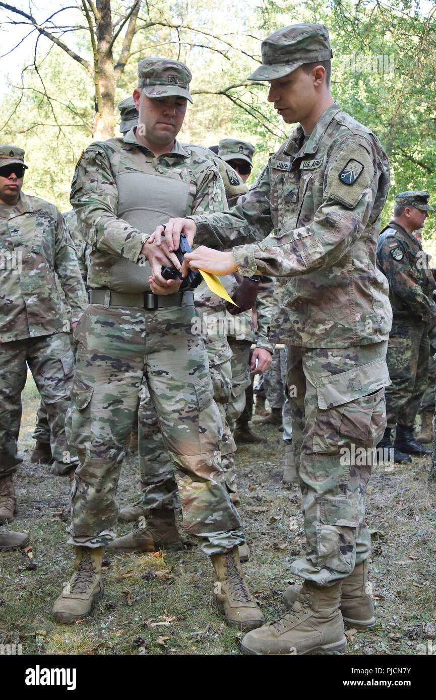 Le sergent de l'armée américaine. Michael Janish, droit, avec le 18e Bataillon de soutien au maintien en puissance de combat interprète la manipulation d'un pistolet P8 au cours d'une formation sur les armes allemandes, la familiarisation et l'épreuve de qualification pour démontrer l'interopérabilité et de renforcer le partenariat de la cohésion sociale à la 7e Armée, le commandement de l'aire d'entraînement Grafenwoehr, Allemagne, le 20 juillet 2018. Banque D'Images