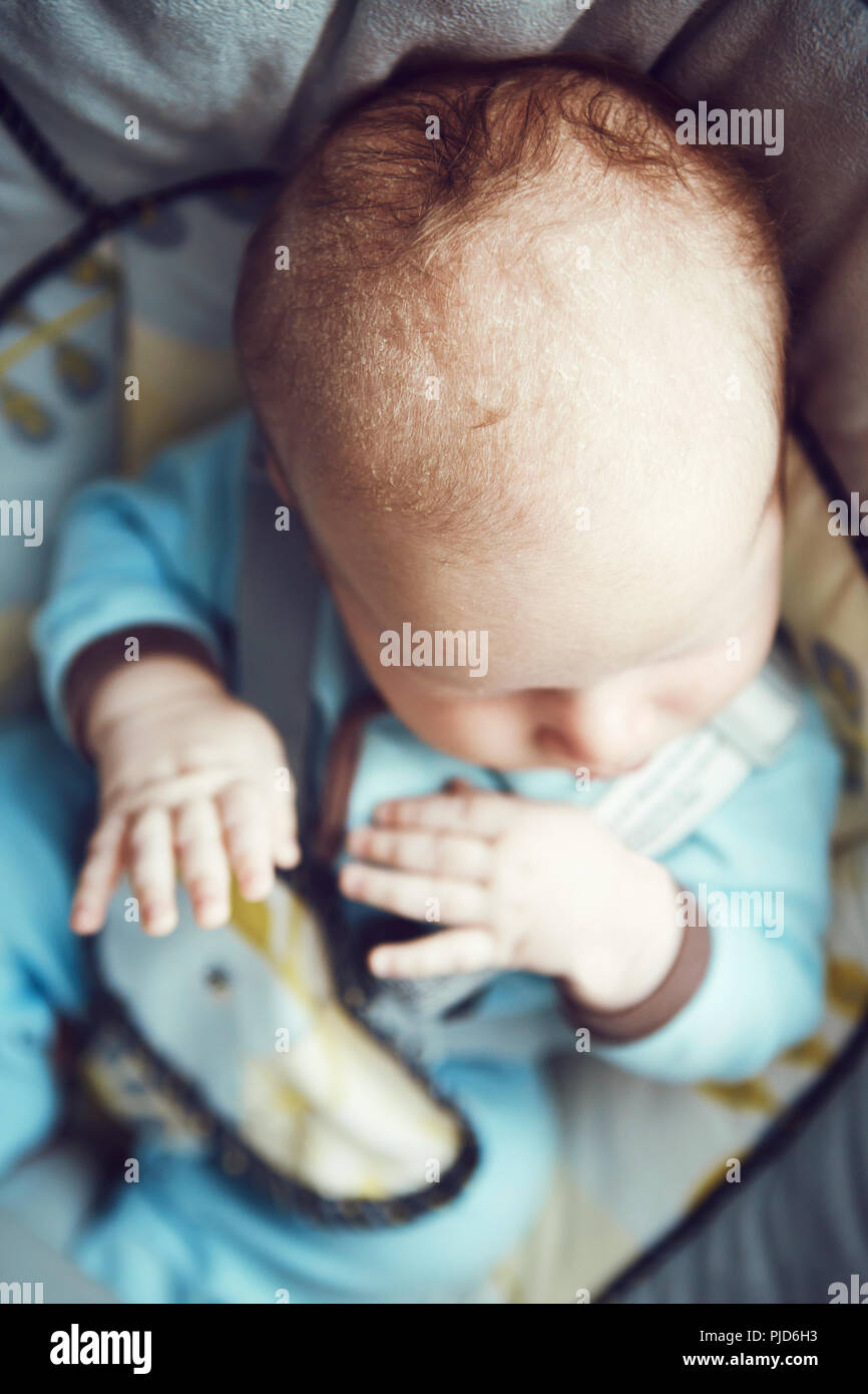 Portrait of cute adorable petit bébé garçon dormir caucasienne dans nouveau-né vêtements bleu assis dans balançoire, vue sur la tête de mains top abo Banque D'Images