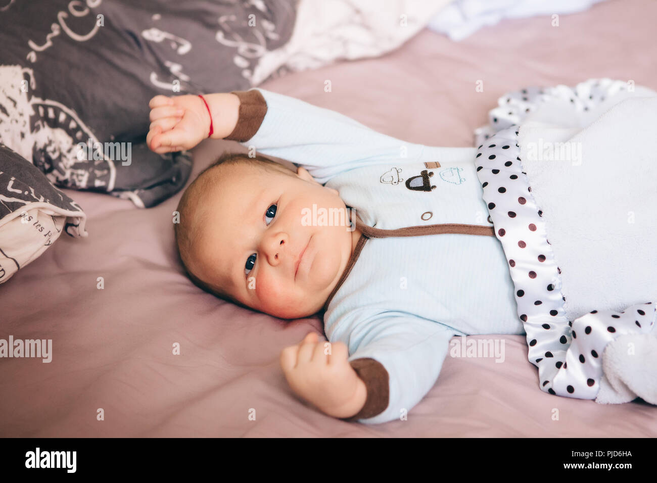 Portrait Of Cute Adorable Blonde Drole De Race Blanche Blanc Petit Bebe Nouveau Ne Garcon Avec Des Yeux Gris Bleu Allonge Sur Un Grand Lit Des Parents A La Camera En Lifest Photo