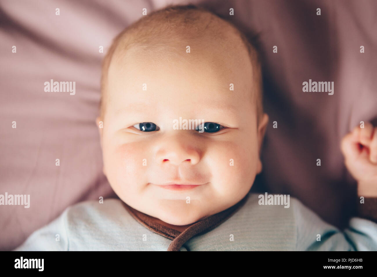 Closeup Portrait Of Cute Adorable Blonde Drole De Race Blanche Blanc Petit Bebe Nouveau Ne Garcon Avec Des Yeux Gris Bleu Lying On Bed A La Camera En Souriant La Vie Photo Stock
