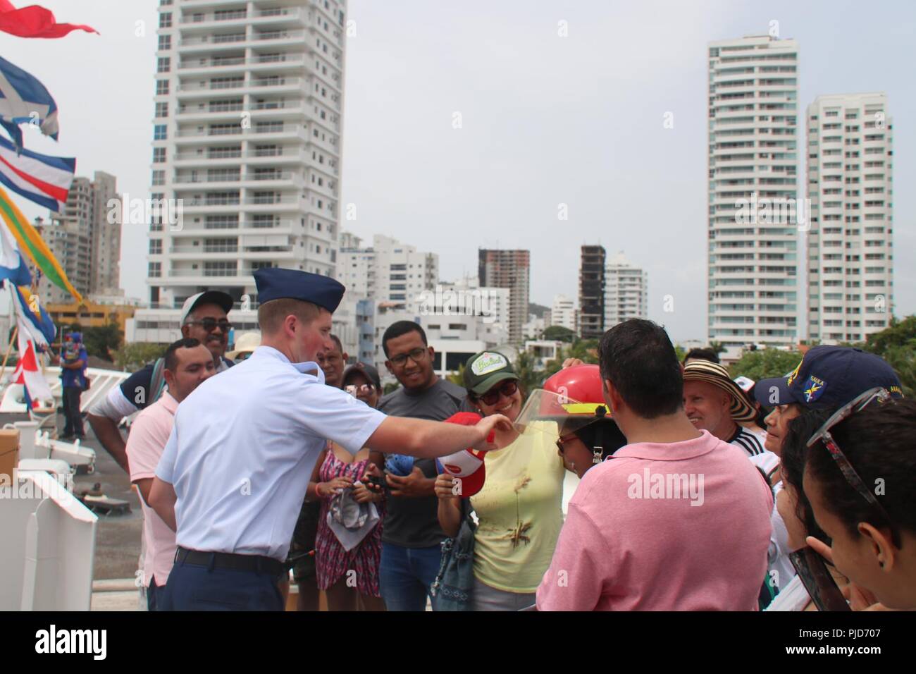 Maître de 2e classe David Rice, un dommage controlman à bord du garde-côte de Hamilton, contribue à une femme de porter un casque de pompier, le 24 juillet 2018, à voile Cartagena de Indias en 2018 à Cartagena, Colombie. L'équipage a effectué des visites publiques de Hamilton de l'outil de coupe lors de leur visite à Carthagène. Banque D'Images