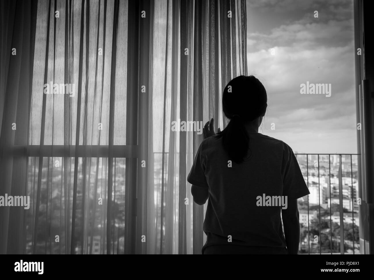 Triste adult Asian woman looking out of window et de penser. Stressés et déprimés jeune femme. Le désespoir des femmes avec des cheveux longs et T-shirts article par e Banque D'Images