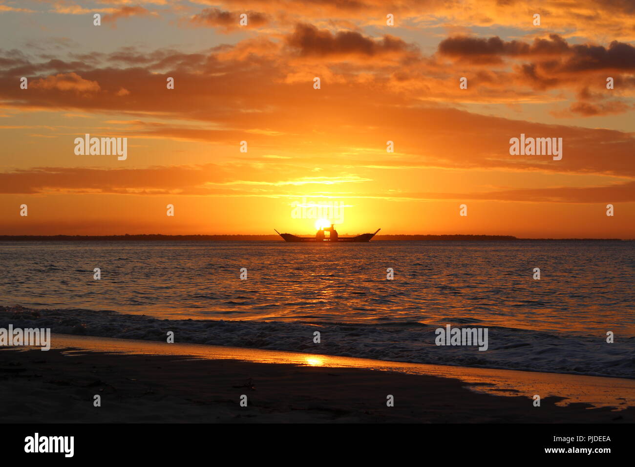 Coucher de soleil sur la plage à Inskip Point, à l'extérieur, vers l'île de Fraser comme un bateau près de l'horizon passe. Banque D'Images