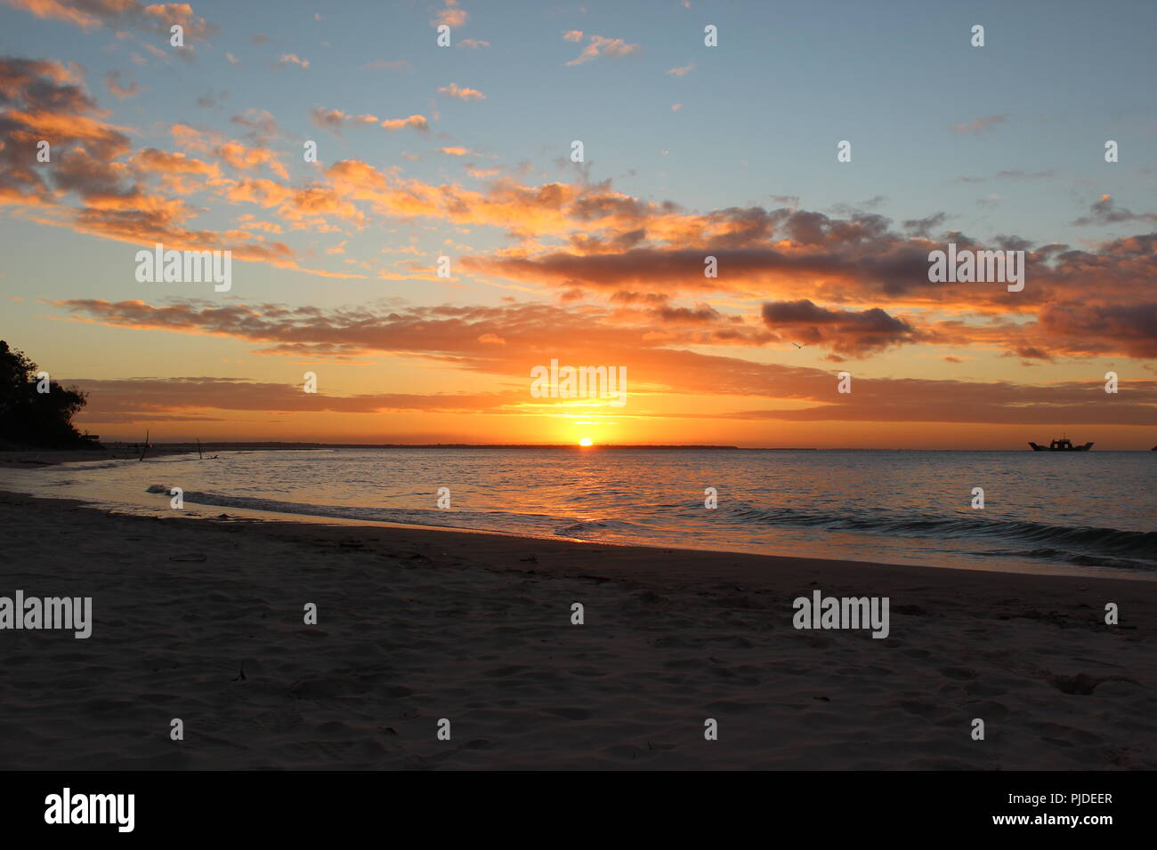 Coucher de soleil sur la plage à Inskip Point, à l'extérieur, vers l'île de Fraser comme un bateau près de l'horizon passe. Banque D'Images