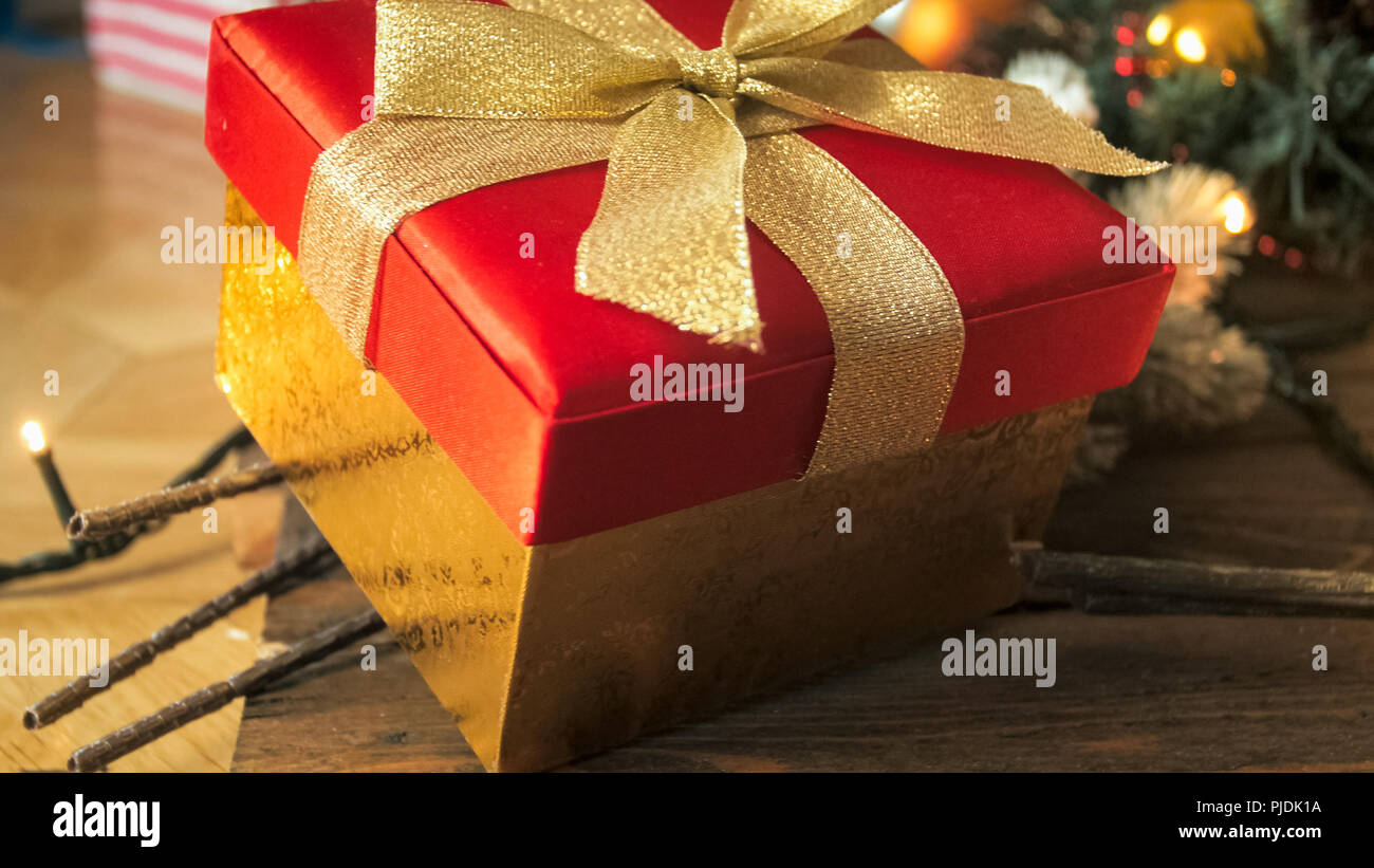 Photo gros plan de red Christmas gift box with golden ribbon bow sur backgrouind en bois Banque D'Images