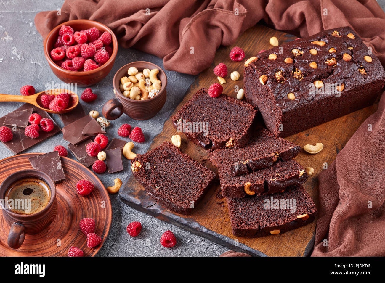 Close Up De Sarrasin Gateau Au Chocolat Livre Avec Les Ecrous Et Les Framboises Coupees En Tranches Sur Une Planche En Bois Sur Une Table En Beton Avec Tasse De Cafe Et Brown